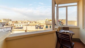 A balcony with a view of a cityscape, a table with a chair, and a vase with flowers. - Saint Peter View - Saint Peter View 2 pax (Rome)