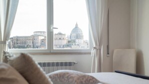 A bedroom with a view of a cityscape through a window, including a prominent dome building. - Saint Peter View - Saint Peter View 2 pax (Rome)