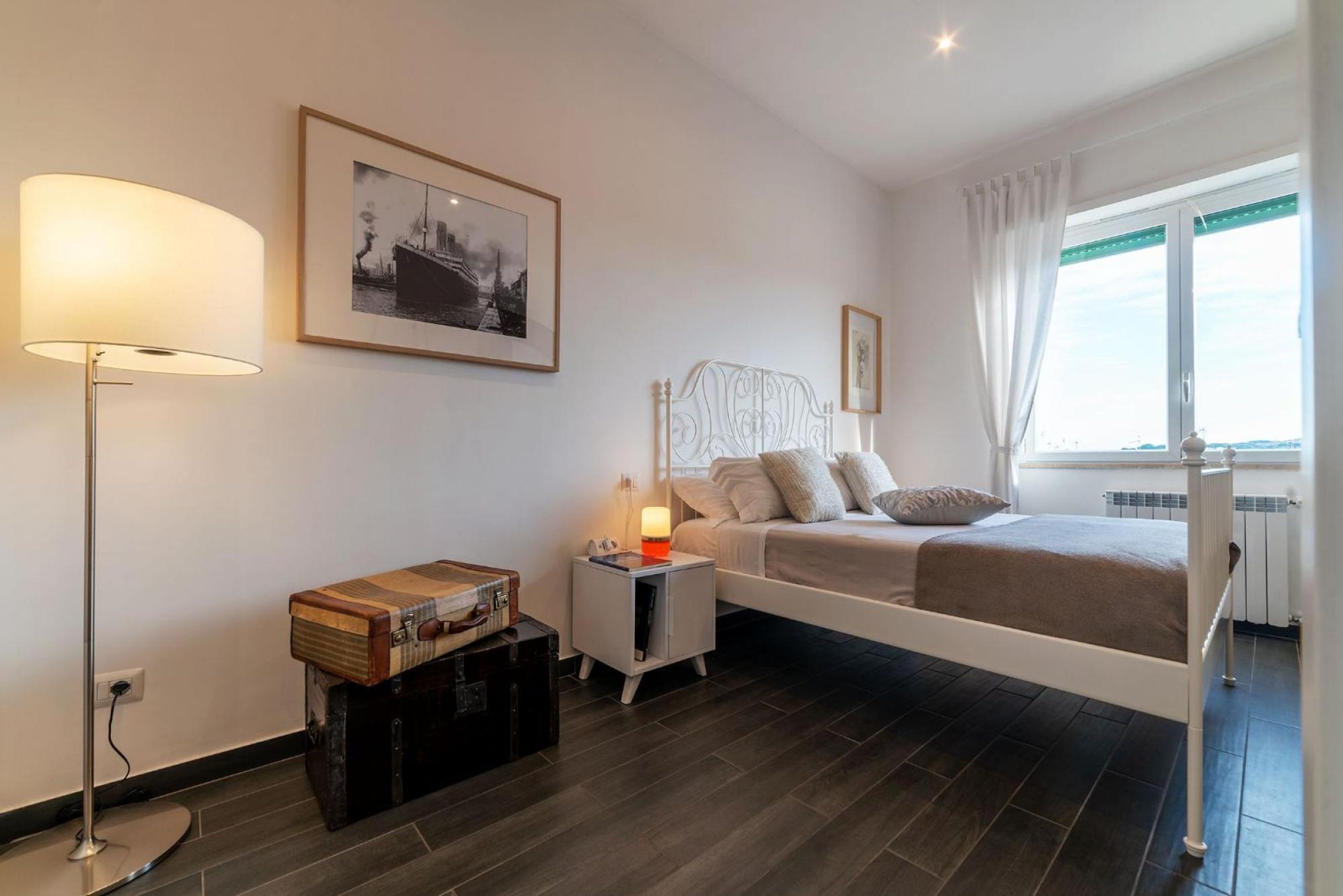 A bedroom with a bed, bedside table, lamp, and a framed picture on the wall.