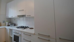 A modern kitchen with white cabinets, a gas stove, and a built-in oven. - Vatican Corner Family Apartment - Vatican Corner Family (Rome)