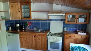 A compact kitchen with wooden cabinets, a white stove, and a sink. - Quiet, bright house (Wissant)