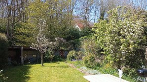A backyard with a wooden picnic table, a barbecue grill, and a shed. - Quiet, bright house (Wissant)