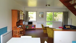 A spacious living area with a wooden cabinet, a TV, a sofa, and a dining table. - Quiet, bright house (Wissant)