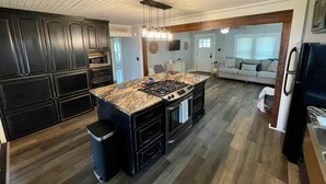 Een moderne keuken met donkere kastjes, een granieten kookeiland en een centraal geplaatst fornuis.
