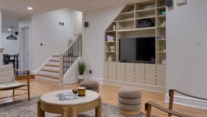 Een moderne woonkamer met een trap, een flatscreen televisie, inbouwplanken en een eethoek.