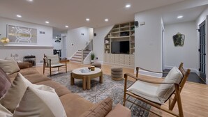 A modern living room with a sofa, chairs, a coffee table, and a TV. - Central Luxury 3-Level Home - Rooftop + Garage (Lancaster)