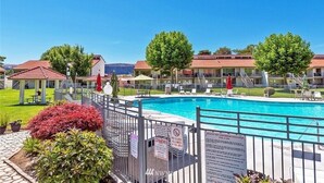 Uma área de piscina com um deck cercado, espreguiçadeiras e um gazebo.