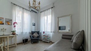 A modern living room with a sofa, a chair, a small table with a plant, and a TV on the wall. - Penthouse Alisa - Penthouse Alisa (Rome)