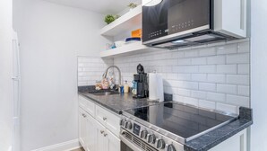 Ett modernt kök med vita skåp, en spis i rostfritt stål och en svart mikrovågsugn.