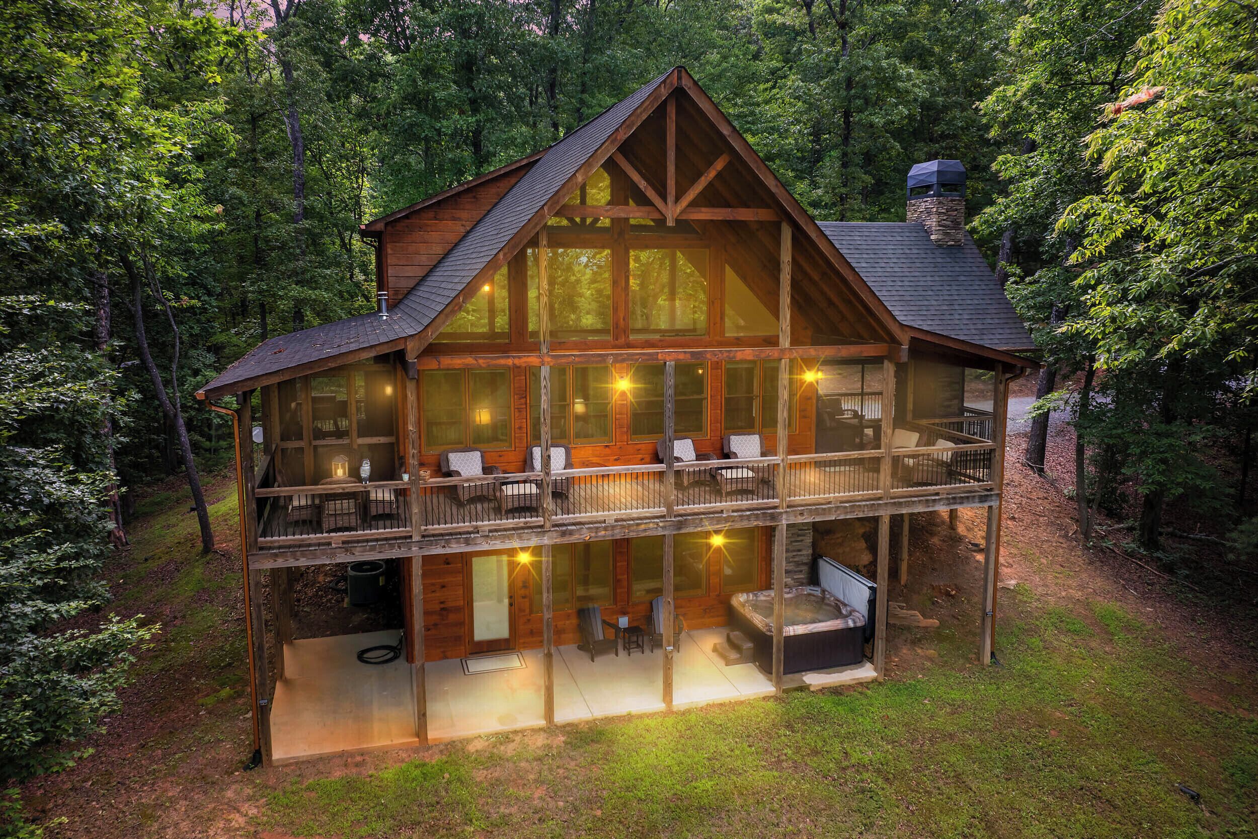 Une cabane en bois à deux étages, dotée d’un balcon, de grandes fenêtres et d’un jacuzzi.