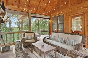 Une terrasse en bois avec des meubles en osier, un seau en métal et une rambarde en verre.