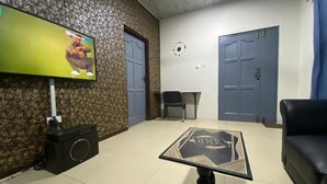 Un salón con televisor, una mesa de diseño geométrico, un sofá y una puerta.