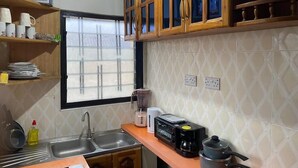 Una cocina con armarios de madera, una ventana, un lavamanos, un tostador y una cafetera.