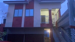Una casa de dos pisos con garaje, escaleras y un balcón.