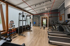 Un gimnasio con equipo cardiovascular, máquinas de pesas y suelo de madera.