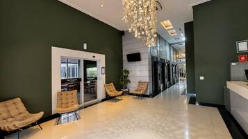 A modern lobby with a chandelier, seating area, and a reception desk.