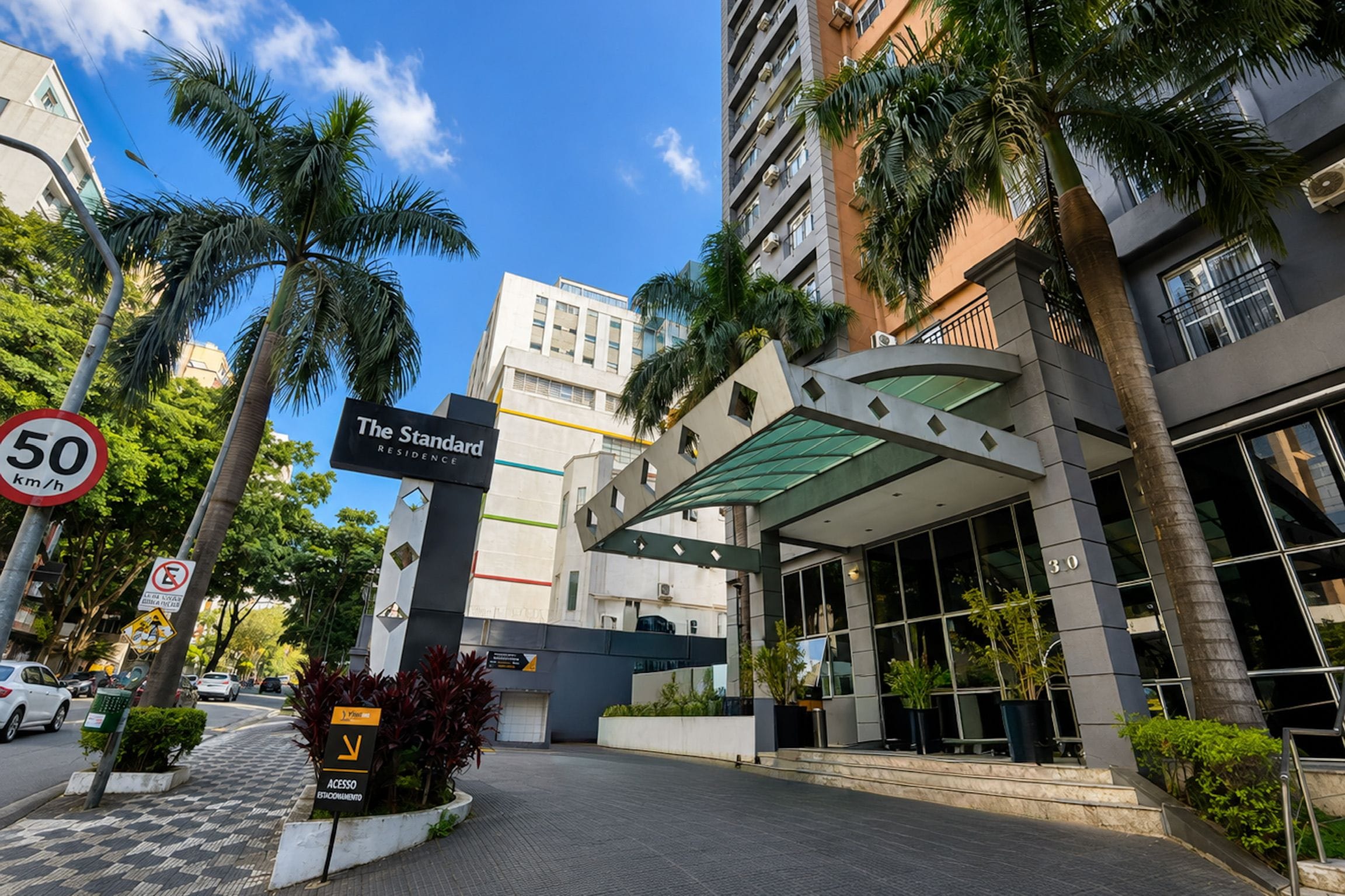 Um edifício moderno com uma placa indicando 'The Standard Residence' e uma placa de limite de velocidade de 50 km/h.