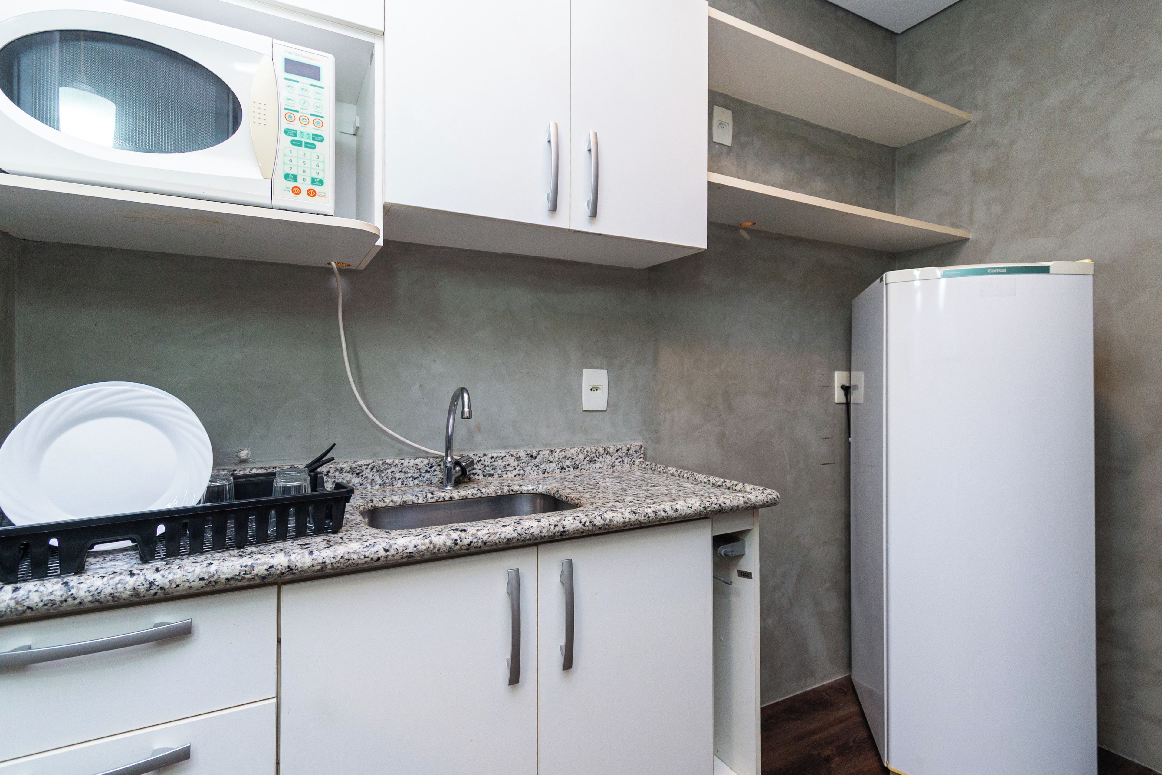 A kitchen with a built-in microwave, a sink, and a refrigerator.