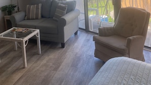 En stue med sofa, lænestol og sofabord i glas.