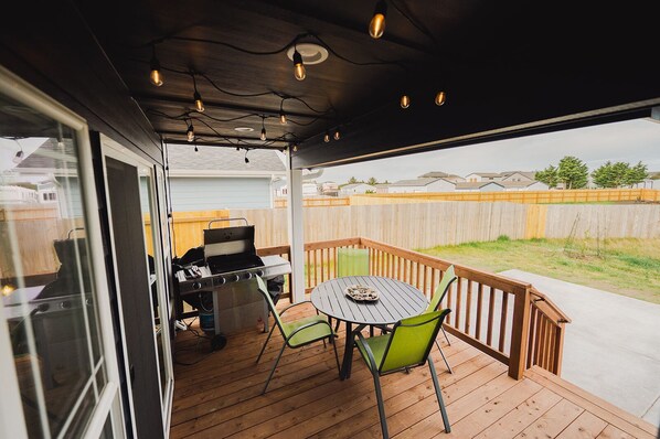 A covered patio with a grill, a table, and chairs. - Adventurer Beach House, short walk to beach! (Ocean Shores)