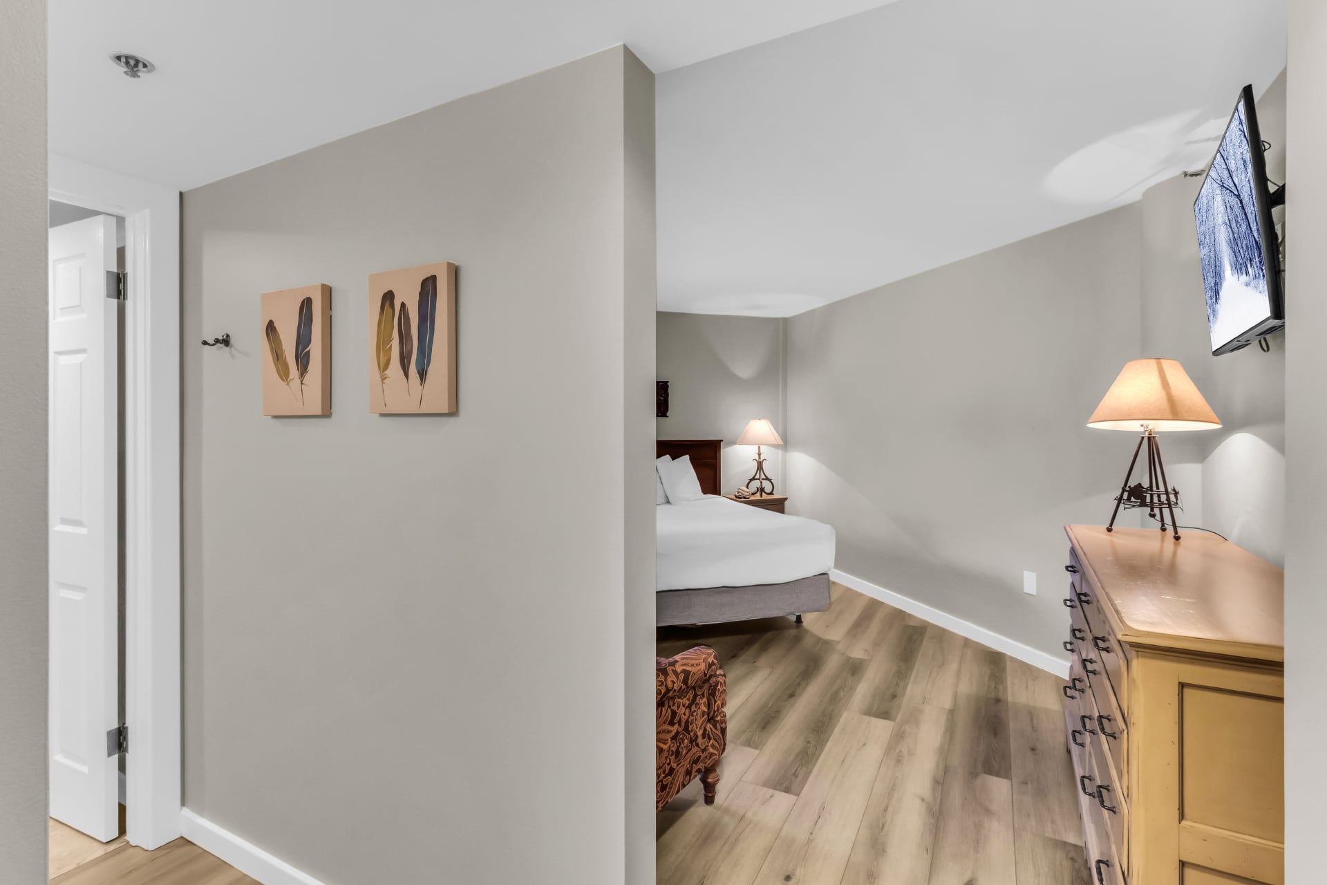 A bedroom with a bed, bedside table, lamp, and a wall-mounted TV.