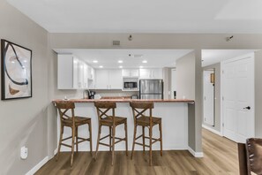 Una cocina moderna con armarios blancos, un refrigerador de acero inoxidable y una encimera de mármol.