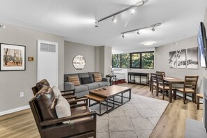 A modern living room with a sofa, coffee table, and dining area with chairs.