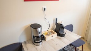 Een moderne keuken met een koffiezetapparaat, waterkoker en een klein kastje.