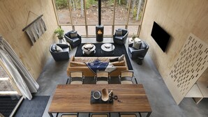 A modern interior with a large window, a fireplace, a dining area, and a seating arrangement. - Scandinavian Chalet with Sauna in Lutsen - Blue (Lutsen)