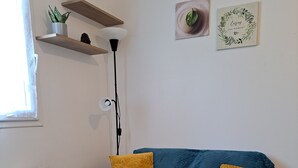 A living room with a blue sofa, yellow cushions, a white coffee table, and a plant on a shelf. - Studio Calme Brest Hyper Centre (Brest)