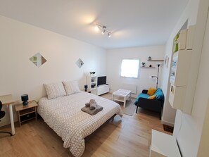 A modern bedroom with a large bed, a desk, a chair, a small table, a sofa, and a TV. - Studio Calme Brest Hyper Centre (Brest)