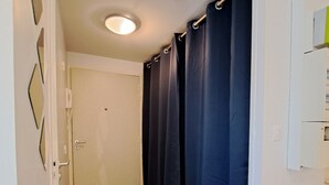 A narrow hallway with wooden flooring, a white door, and a blue curtain. - Studio Calme Brest Hyper Centre (Brest)