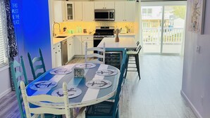 Een moderne keuken met witte kasten, een centraal eiland en een eethoek met een blauw-witte tafel en stoelen.