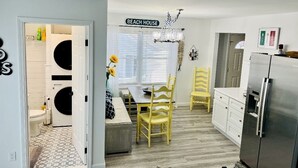 Een keuken met een eethoek, een koelkast en een bordje met de tekst 'BEACH HOUSE'.