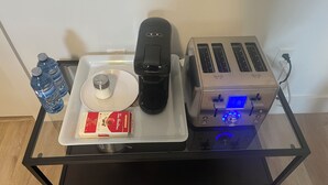 Un comptoir de cuisine avec un grille-pain, une machine à café, une bouteille d’eau, un moulin à poivre et une boîte de crème à café.
