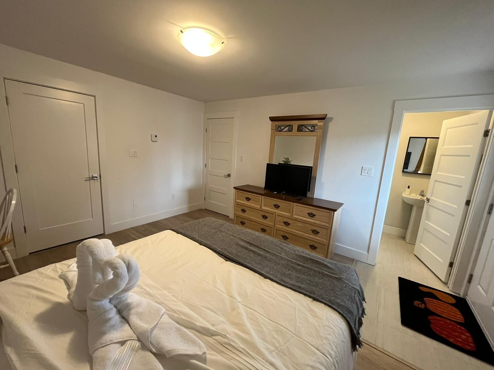 Een slaapkamer met een bed, een dressoir, een televisie en een deur.