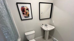 Une salle de bain avec des toilettes, un lavabo et une œuvre d’art encadrée au mur.
