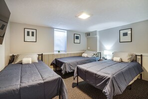 A room with three single beds, a window with blinds, a ceiling light, and framed pictures on the walls. - Inviting Minneapolis Vacation Rental w/ Game Room! (Minneapolis)