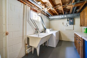 A laundry room with a sink, washing machine, and wooden cabinets. - Inviting Minneapolis Vacation Rental w/ Game Room! (Minneapolis)
