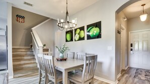 Un comedor con mesa y sillas de madera, una araña y decoración en las paredes.