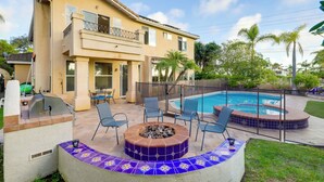 Une maison à deux étages avec un patio à l’arrière, une piscine et un foyer extérieur.