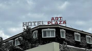 A hotel with a sign reading 'HOTEL PLAZA ART' and another sign below it that reads 'RAKAT MAHALLASIGA XUSH KELIBSIZ.'