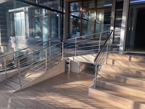 A modern interior with a glass railing staircase, a metal handrail, and a tiled floor. - Art Plaza (Tashkent)