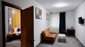 A room with a bed, a sofa, a small table, and a TV mounted on the wall. - Art Plaza (Tashkent)