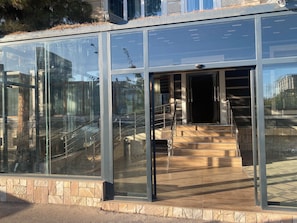 Un bâtiment moderne doté de grandes fenêtres en verre, d’un socle en pierre et d’un escalier menant à l’entrée.
