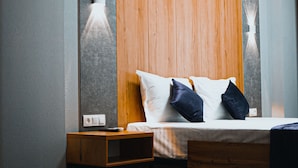A modern hotel room with a wooden headboard, a bedside table, and a nightstand. - Art Plaza (Tashkent)