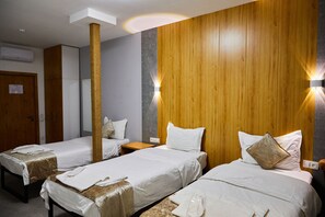 A hotel room with two single beds, a wooden accent wall, and a small wooden nightstand.