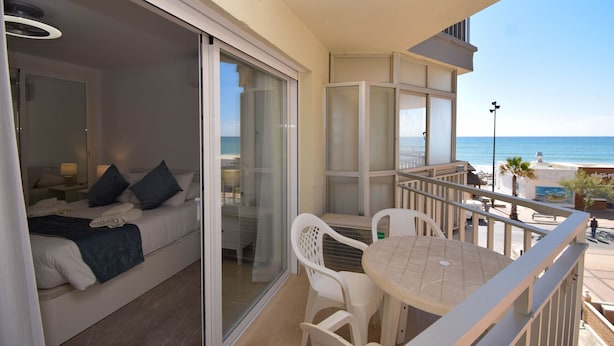 Un balcon avec vue sur la mer, un canapé avec des coussins, une table et des chaises.