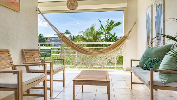 A room with a hammock, wooden furniture, and a view of palm trees. - Cocon Dumyse, proche du Jardin botanique (Petit-Bourg)
