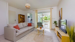 A modern living room with a sofa, coffee table, and TV stand. - Cocon Dumyse, proche du Jardin botanique (Petit-Bourg)